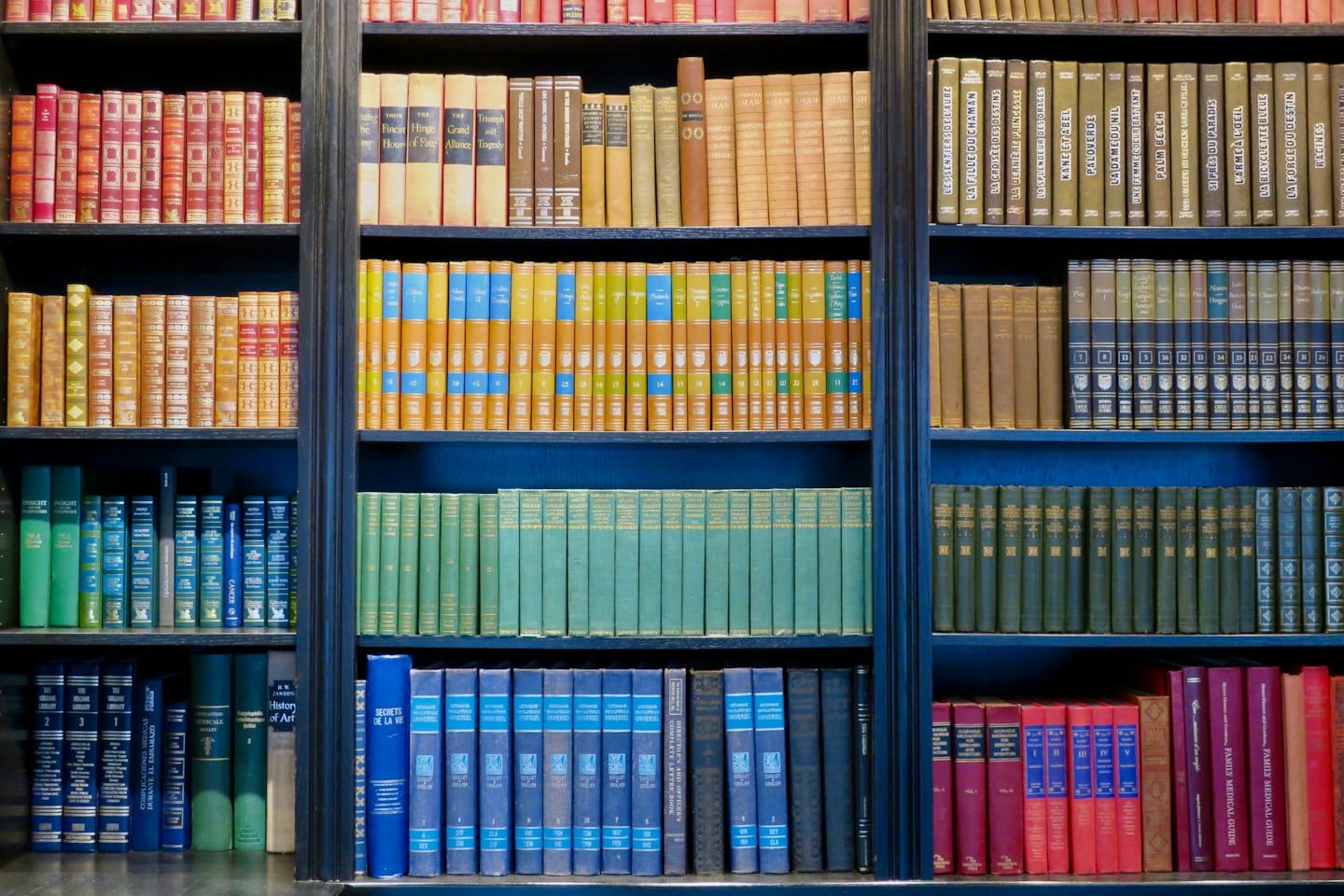 Parete di vecchi libri su molti scaffali di una biblioteca.